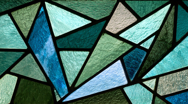A close-up showcasing a textured stained glass window featuring an abstract blue and green geometric pattern.
