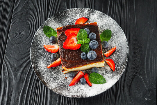delicious freshly baked Basque cheesecake on a black wooden rustic background