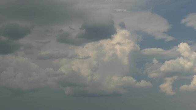 a tall cumulus cloud grows and swirls in the blue sky on a timelapse video