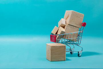 A miniature shopping cart loaded with blank wooden cubes representing parcels on a blue background. High Quality Photo © 7TridentSea