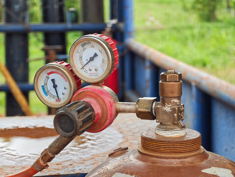 Acetylene gas cylinder with pressure gauge and regulator valve, keep at the welder workshop. It using for metal welding job. Industrial equipment object, close-up with selective focus.