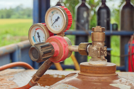 Acetylene gas cylinder with pressure gauge and regulator valve, keep at the welder workshop. It using for metal welding job. Industrial equipment object, close-up with selective focus.