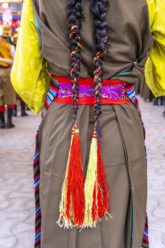 National Day of the Tibetan Uprising in Dharamsala, Himachal Pradesh, India. A woman with braided hair adorned with red and green tassels.