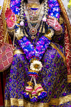A statue adorned with flowers and jewelry at the Mata Lal Devi Temple in Amritsar, India. The statue is adorned with garlands and traditional clothing.