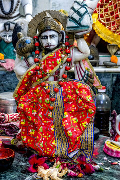 A statue of Hanuman, adorned with garlands and colorful clothing, in a street temple in Kolkata, West Bengal, India