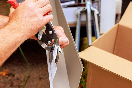 Person using shears tool to cut strap while packing box outside