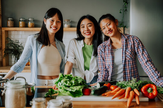 Happy beautiful chinese women friends bonding at home