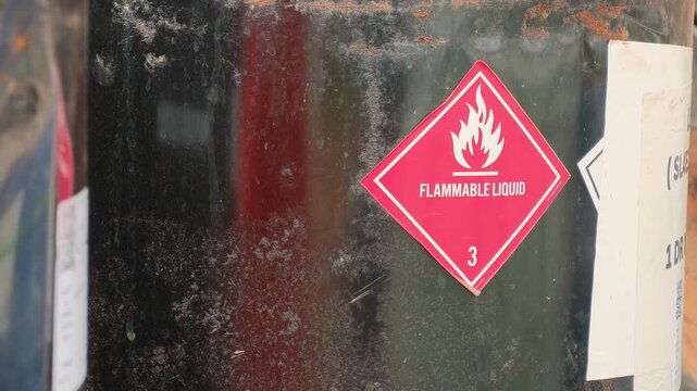 Flammable liquid warning sign on the chemical metal barrel. Industrial safety sign on the object, close-up with selective focus.