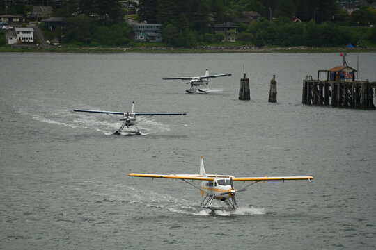 Multiple floatplanes taxi across the water after arriving in Ketchikan, Alaska, where seaplane aviation is an essential part of the regional transportation network. With many Southeast Alaska communit