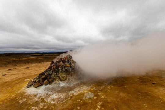 Steam venting intensely from a stone cairn fumarole surrounded by sulfur deposits in Hverir geothermal area near Lake M&yacute;vatn Iceland
