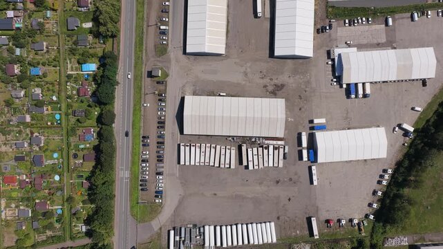 Aerial top-down view of industrial warehouse and truck parking lot with heavy traffic