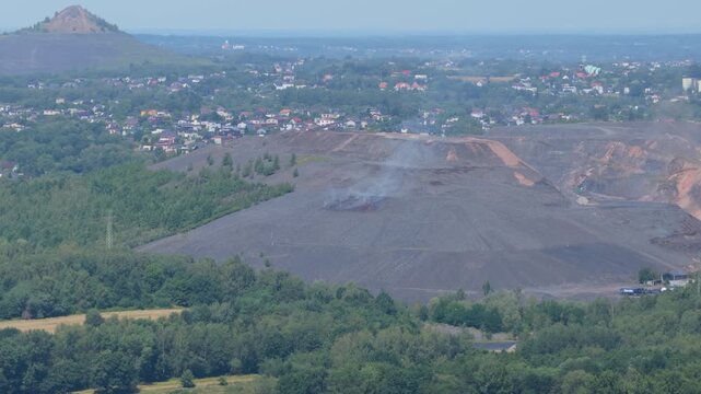 Smoking slag heap from coal mine polluting the air with smoke and dust