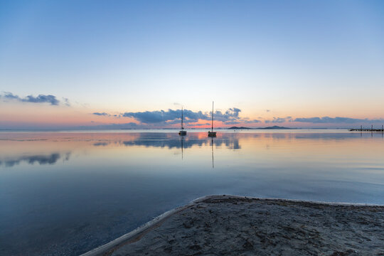 View of the Mar Menor at dawn with two boats on its waters, Punta Prima, Cartagena, Region of Murcia, Spain