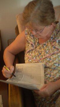 A senior woman portrait solving a Sudoku puzzle at home
