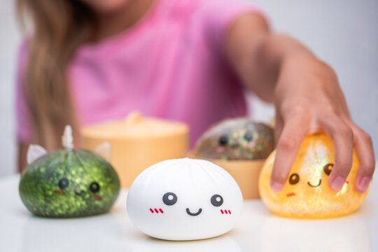 Girl Reaching for Colorful Dumpling Toys, Sensory Squishy Toy Collection with copy space

