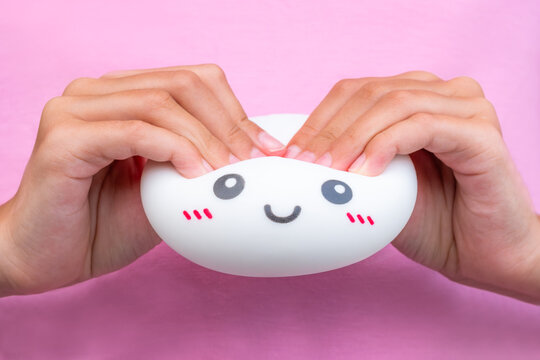 Child hands squeezing white Dumpling Toy against pink shirt, sensory fidget play and tactile toy concept with copy space
