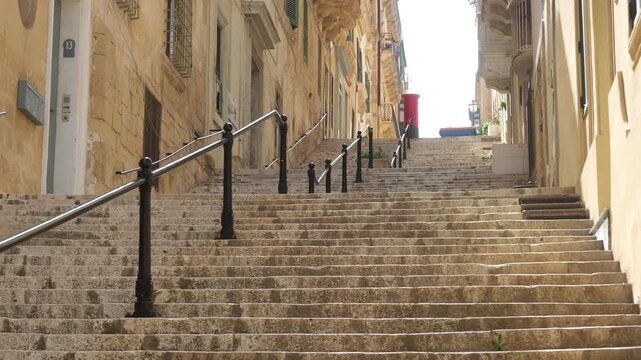 stepped street descends through valletta narrow stairway a distant postbox marking the historic old town route valletta side street cobbled street narrow malta street old town street historic street