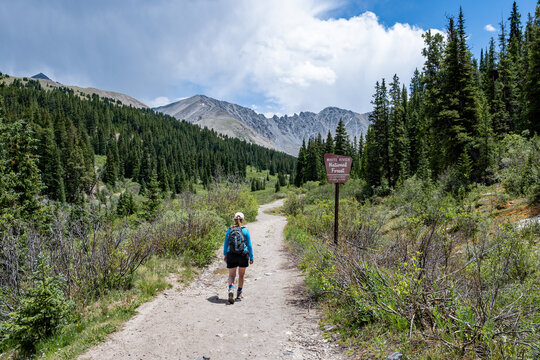 Woman hiking on Mayflower Gulch Trail near Copper Mountain and Leadville, Colorado under stormy summer cloudscape.