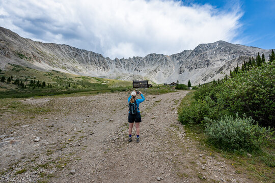 Woman hiking on Mayflower Gulch Trail near Copper Mountain and Leadville, Colorado under stormy summer cloudscape.
