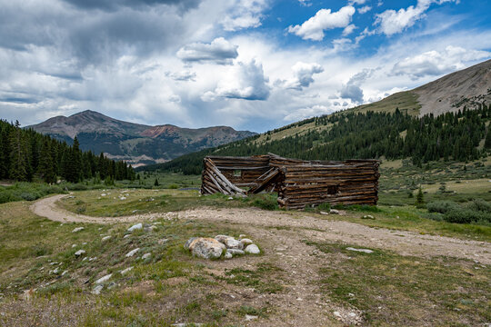 Ruins of former mining cabins on Mayflower Gulch Trail near Copper Mountain, Colorado under summer afternoon cloudscape.