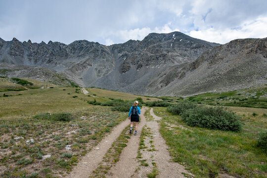 Woman hiking on Mayflower Gulch Trail near Copper Mountain and Leadville, Colorado under stormy summer cloudscape.
