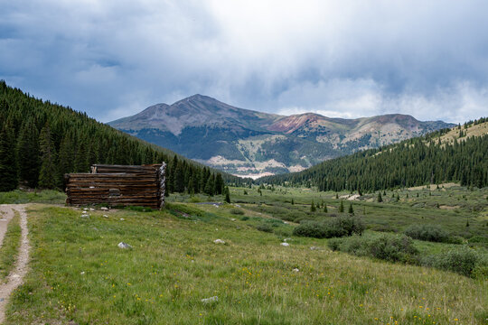 Ruins of former mining cabins on Mayflower Gulch Trail near Copper Mountain, Colorado under summer afternoon cloudscape.