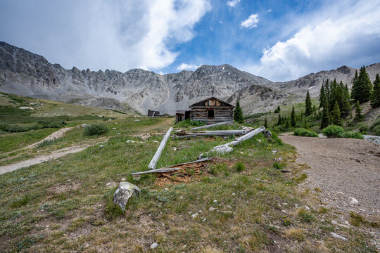 Ruins of former mining cabins on Mayflower Gulch Trail near Copper Mountain, Colorado under summer afternoon cloudscape.