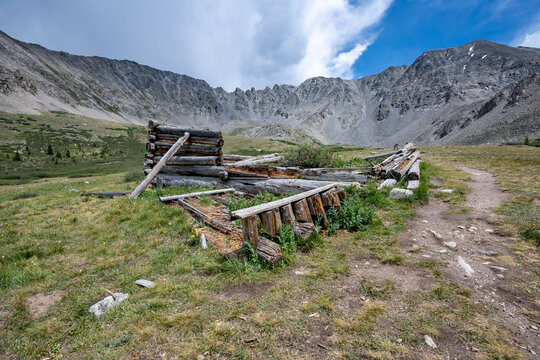Ruins of former mining cabins on Mayflower Gulch Trail near Copper Mountain, Colorado under summer afternoon cloudscape.