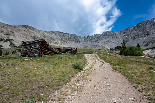 Ruins of former mining cabins on Mayflower Gulch Trail near Copper Mountain, Colorado under summer afternoon cloudscape.