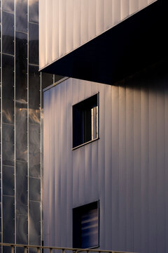 Deep shadows cut across windows in a minimal study of architecture, while the urban facade uses contrast and geometry to define the building exterior planes.