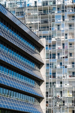 Blue glass catches light across windows in a close study of architecture, while the urban facade shifts through grid geometry and contrast over the layered building planes.