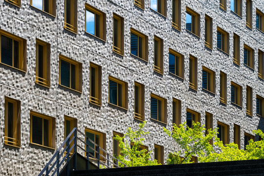 Yellow windows punctuate texture in a close study of architecture, as the urban facade develops a measured pattern across the building exterior through strict geometry.