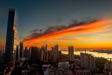 Fototapeta premium Wuhan CBD skyline illuminated by a dramatic fiery sunrise. These brilliant burning clouds above towering skyscrapers symbolize a blazing, prosperous economy and the dawn of a dynamic financial future