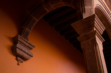 Detail of stone arch, corbel and pillar made of pink quarry stone at Antigua Casa de Moneda in San Luis Potosi, Mexico. Mexican colonial Baroque architecture with wooden beam ceiling. © Pablo