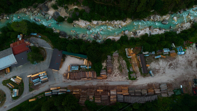 aerial view of a village with river and buildings in neutral calm setting from above with concrete, wood, and metal materials and green, brown, blue, and red colors.