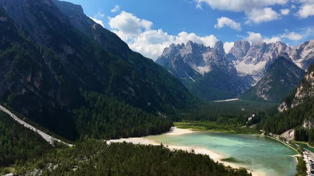 peaceful mountain landscape observed from a high vantage point in a scenic valley with a lake and forested areas, featuring rocky mountains, water, and trees under a green and blue sky.