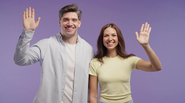 Happy Young Couple Waving Hands At Camera With Friendly Smiles, Man And Woman Saying Hello, Hi Or Goodbye, Warm Greeting And Welcoming Gesture For Communication And Lifestyle Content