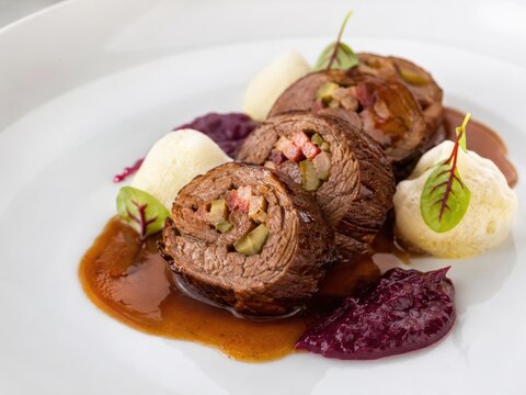 Aufgeschnittene deutsche Rinderroulade mit herzhafter F&uuml;llung, Rotkohl, Kartoffelbeilage und dunkler Bratensauce. Klassische Hausmannskost als deutscher Klassiker modern angerichtet.