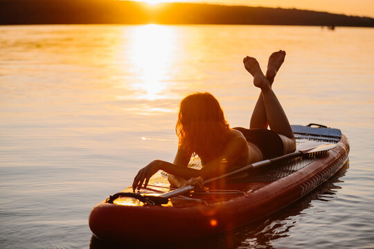 Woman relaxing on paddleboard enjoying sunset water