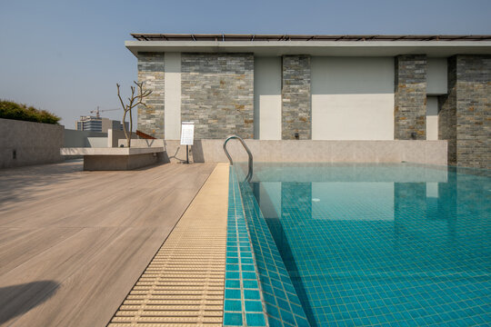 Rooftop Swimming Pool with Wooden Deck and Stone Wall of a Modern Residential Building
