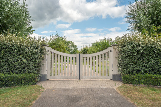 Closed white gate at the entrance to a Dutch estate in the province of South Holland. The photo was taken on a cloudy day in the summer season.
