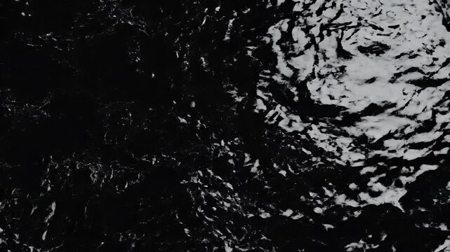 Dark, rippling water surface with light reflecting, creating a textured abstract