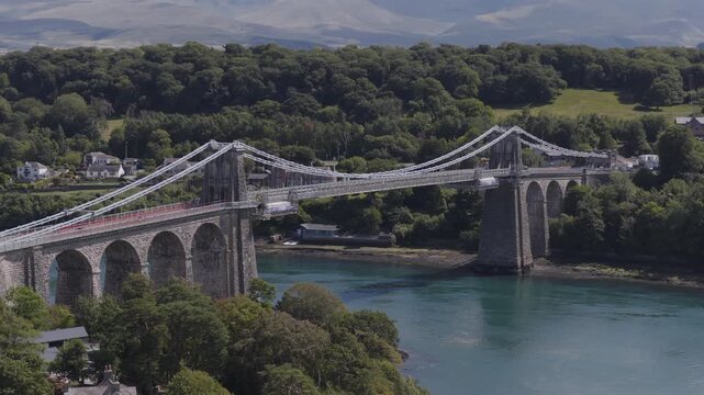 Establishing aerial view of the Menai Suspension Bridge which crosses the Menai Straits to connect the island of Anglesey and the mainland of Wales.
