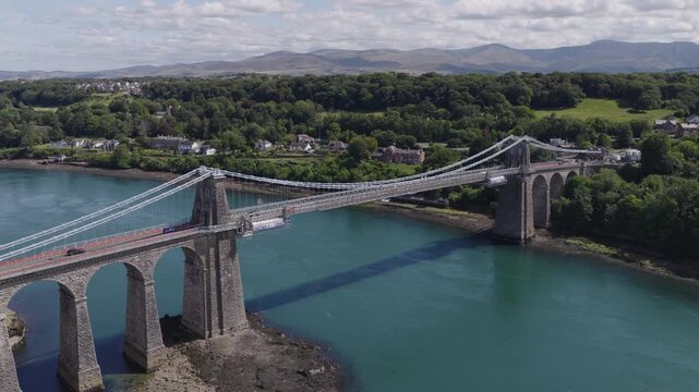 Establishing aerial view of the Menai Suspension Bridge which crosses the Menai Straits to connect the island of Anglesey and the mainland of Wales.