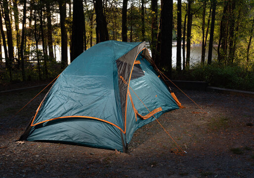 Glowing blue backpacking tent pitched near a lake