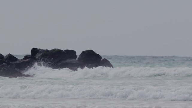 Telephoto shot of Slow motion waves hitting rocks in tortuga bay beach Galapagos