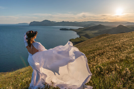 Woman hat dress, silhouette of a woman in a flowing white dress and hat looking at the sea landscape at sunset