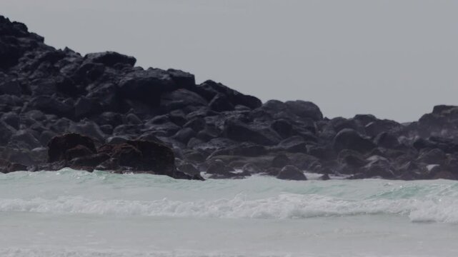 Telephoto shot of Slow motion waves hitting rocks in tortuga bay beach Galapagos