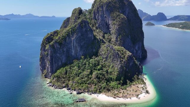 High aerial drone orbit above the top of a dramatic limestone island with surrounding tropical islands visible across the sea in El Nido, Palawan, Philippines. The elevated perspective reveals rugged 