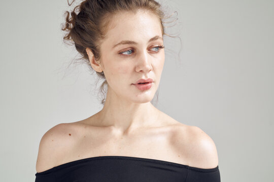 Woman poses indoors with casual expression and simple top